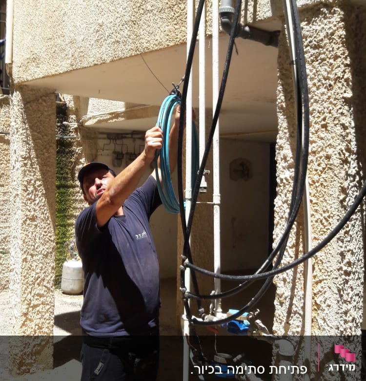 אדם עובד עם צינורות ומד מים על קיר חיצוני